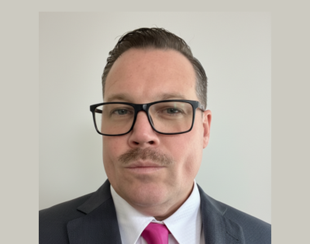 Portrait of Sean McKay Holt in a suit and pink tie