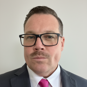 Portrait of Sean McKay Holt in a suit and pink tie